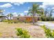 Charming brick home with palm trees and verdant landscaping offers a warm and inviting curb appeal at 891 Palmetto Ne Dr, Port Charlotte, FL 33952