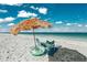 Beach relaxation scene showcasing a straw umbrella, beach chairs, an inflatable tube, and a blanket on the sandy shore at 91 Avenida Veneccia, Sarasota, FL 34242
