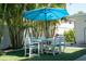 Outdoor dining area with table and chairs under a large umbrella, surrounded by lush palms at 91 Avenida Veneccia, Sarasota, FL 34242