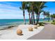 Scenic waterfront view featuring palm trees, decorative stone spheres, and a paved walkway at 91 Avenida Veneccia, Sarasota, FL 34242
