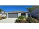 Charming single-story home with a gray two-car garage, well-maintained lawn, and lush tropical landscaping at 9176 Tequila Sunrise Dr, Sarasota, FL 34241