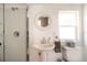 Bright bathroom featuring a glass shower, round mirror above a pedestal sink, and toilet at 1018 Charlotte Ave, Sarasota, FL 34237