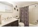 Well-lit bathroom showcasing a vanity, toilet, and a bathtub with a stylish floral shower curtain at 1018 Charlotte Ave, Sarasota, FL 34237
