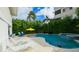 Secluded pool area with lush landscaping, a sun umbrella, poolside lounge chairs, and a built-in spa at 113 8Th S St, Bradenton Beach, FL 34217