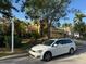 Front view of home with lush landscaping, mature trees, and a white car parked in the driveway at 11516 Sweetflag Dr, Lakewood Ranch, FL 34202