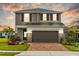 Two-story home with tan siding, brown shutters, manicured landscaping, and a brick driveway at 11591 Little River Way, Parrish, FL 34219