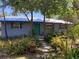 Charming home featuring a blue facade, a green front door, a metal roof, and beautiful landscaping at 1350 40Th St, Sarasota, FL 34234