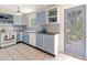 Charming kitchen featuring stylish blue and white cabinets, unique backsplash, and a door to the outdoors at 1350 40Th St, Sarasota, FL 34234
