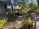 Beautifully landscaped yard with stone pathway and lush tropical plants by the porch and wooden deck at 1350 40Th St, Sarasota, FL 34234