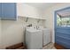 Functional laundry room with washer, dryer, shelving, and bright blue door at 1350 40Th St, Sarasota, FL 34234