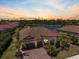 Sunset aerial view of a lovely residence with a tile roof, lush landscaping, and a serene lake backdrop at 20655 Valprato Ct, Venice, FL 34293