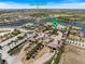 An aerial view of the Community Center featuring a pool, tennis courts, and manicured grounds near a lake at 20655 Valprato Ct, Venice, FL 34293