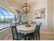 Bright dining area with round table, light fixture, painting of a cow, and a view of the pool at 20655 Valprato Ct, Venice, FL 34293