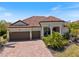 Charming single-story home featuring a tile roof, mature landscaping, and a two-car garage on a sunny day at 20655 Valprato Ct, Venice, FL 34293