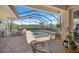 Screened-in pool and spa featuring a brick patio, an outdoor kitchen, and lush greenery views at 20655 Valprato Ct, Venice, FL 34293