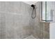 Close-up of tiled walk-in shower featuring a sleek showerhead and tiled walls at 20655 Valprato Ct, Venice, FL 34293