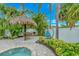 Inviting backyard featuring a tiki hut, outdoor grill, lounge chair, lush greenery and privacy fence at 216 Palmetto Ave, Anna Maria, FL 34216