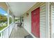 Charming front porch featuring a cozy seating area and a vibrant red door at 216 Palmetto Ave, Anna Maria, FL 34216