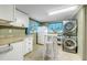 Laundry area with a stacked washer and dryer, white cabinets, and a table with stools at 216 Palmetto Ave, Anna Maria, FL 34216