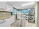 Laundry area with a stacked washer and dryer, white cabinets, and a table with stools at 216 Palmetto Ave, Anna Maria, FL 34216