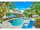 Inviting outdoor space with a swimming pool, lounge chairs, lush greenery, and two-story house view at 216 Palmetto Ave, Anna Maria, FL 34216