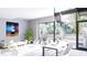 Bright living area with white furniture, large windows showcasing lush landscaping, and a dining table in an open concept layout at 2170 Robinhood St # A1-304, Sarasota, FL 34231