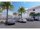 Parking area showcasing luxury vehicles near a modern building with palm tree accents at 2170 Robinhood St # A1-304, Sarasota, FL 34231