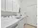 The laundry room features white cabinetry, a sink and modern washer and dryer at 2931 Bravura Lake Dr, Sarasota, FL 34240