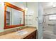 Bathroom featuring wood vanity, granite countertop, decorative shelving, and combined tub shower at 2961 Valencia Rd, Venice, FL 34293
