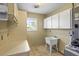 Bright laundry room with a deep utility sink, storage cabinets, and natural light from the window at 2961 Valencia Rd, Venice, FL 34293