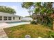 Backyard swimming pool features a brick trim, pergola, lush landscaping, and a white privacy fence at 2961 Valencia Rd, Venice, FL 34293