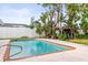 Backyard swimming pool features a brick trim, pergola, lush landscaping, and a white privacy fence at 2961 Valencia Rd, Venice, FL 34293