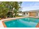 Backyard pool with brick trim next to back exterior of house and lush landscaping at 2961 Valencia Rd, Venice, FL 34293
