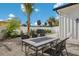 Private backyard showcasing a barbecue grill, a table with four chairs, lush palms and a white fence at 305 73Rd St, Holmes Beach, FL 34217