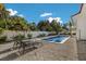 This backyard has a pool, an outdoor barbecue grill, a table with four chairs, palms and a white fence at 305 73Rd St, Holmes Beach, FL 34217
