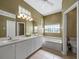 Bathroom with a double sink vanity, tiled flooring, and a tub, creating a functional and stylish space at 3835 Alamanda Dr, Sarasota, FL 34238