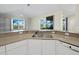Kitchen featuring granite countertops, white cabinetry, and views of the water and lanai at 3835 Alamanda Dr, Sarasota, FL 34238