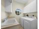 The laundry room features a sink, washer, dryer, storage cabinets, and a charming window at 3835 Alamanda Dr, Sarasota, FL 34238