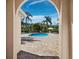 Community pool surrounded by mature landscaping and brick pavers, seen through an archway at 3835 Alamanda Dr, Sarasota, FL 34238