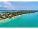 An aerial view displays homes lining the beach fronting clear turquoise water at 4050 Higel Ave, Sarasota, FL 34242