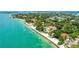 Aerial view of a luxury waterfront home with private beach access surrounded by lush greenery at 4050 Higel Ave, Sarasota, FL 34242