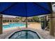 Community pool and hot tub with blue gazebo, lounges, and building with tan walls and brown roof at 4061 Crockers Lake Blvd # 2618, Sarasota, FL 34238