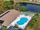 Aerial view of a pool and shuffleboard court with blue sky and adjacent lake at 4169 66Th Street W Cir # 4169, Bradenton, FL 34209