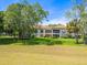 Beautiful building exterior with balconies overlooking a lush green lawn, framed by mature trees and landscaping at 4355 Longmeadow # 23, Sarasota, FL 34235