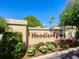 Entrance to Woodland Grove community with colorful landscaping and a clear blue sky at 4355 Longmeadow # 23, Sarasota, FL 34235