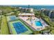 Aerial view of the tennis court and pool, surrounded by lush green trees at 4500 Gulf Of Mexico Dr # Ph4, Longboat Key, FL 34228