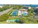Aerial view featuring tennis courts, swimming pool, shuffleboard, and clubhouse against backdrop of trees and blue water at 4500 Gulf Of Mexico Dr # Ph4, Longboat Key, FL 34228