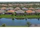 An aerial view shows the home surrounded by a lush lawn, bordered by a lake, and mature landscaping at 4726 Zeno Ct, Bradenton, FL 34211