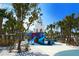 Outdoor playground featuring colorful slides, towers, and palm trees in a safe, sandy environment at 5502 Shadow Lawn Dr, Sarasota, FL 34242