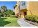 Inviting yellow two-story home featuring a well-manicured lawn and charming walkway at 5691 Bentgrass Dr # 15-101, Sarasota, FL 34235